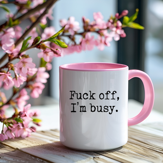 Fuck off mug that is white and pink handled with "fuck off, I'm busy" text.