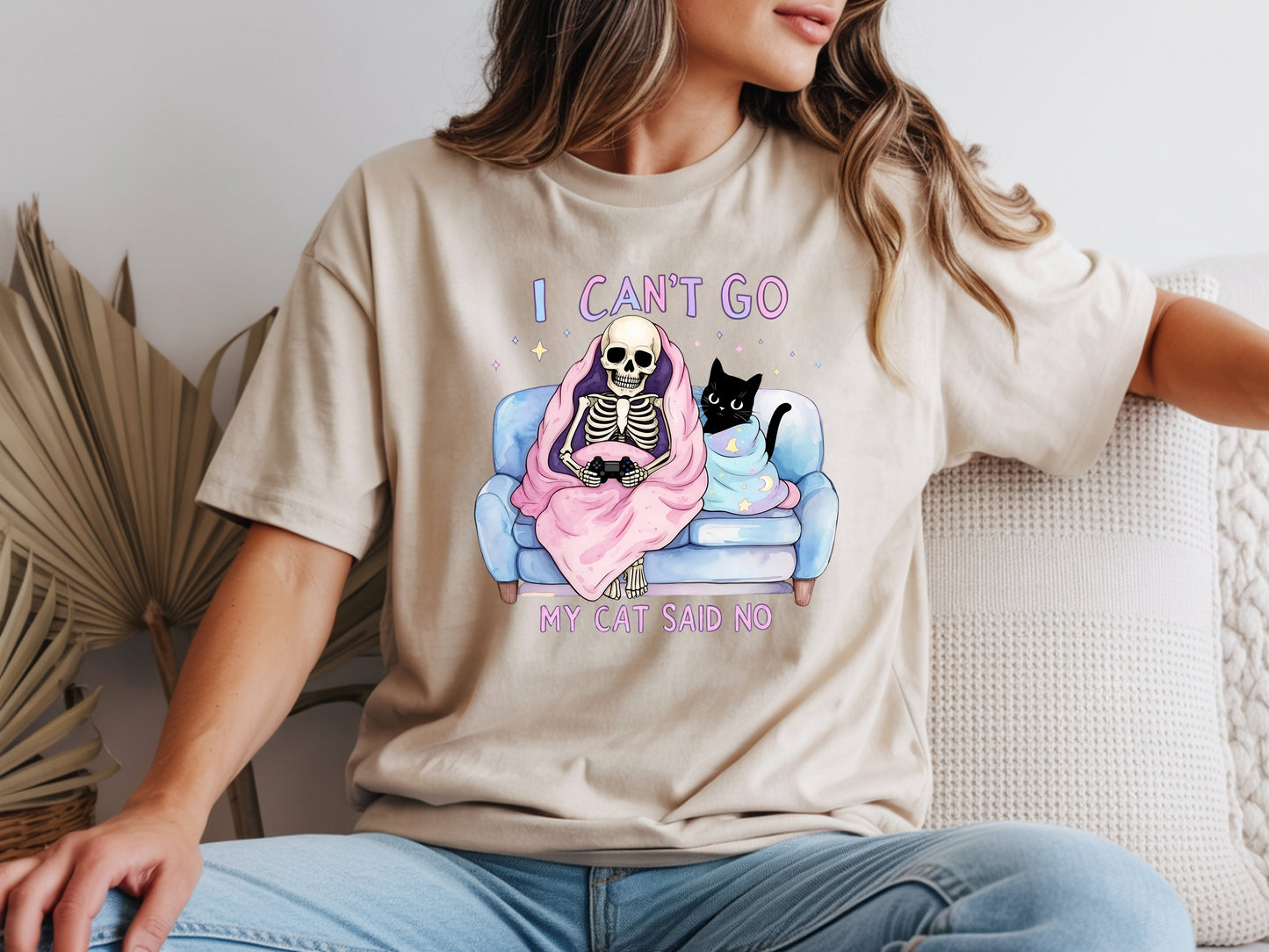 Person wearing beige unisex cat lover graphic tee with “I Can’t Go My Cat Said No” quote and skeleton cat design