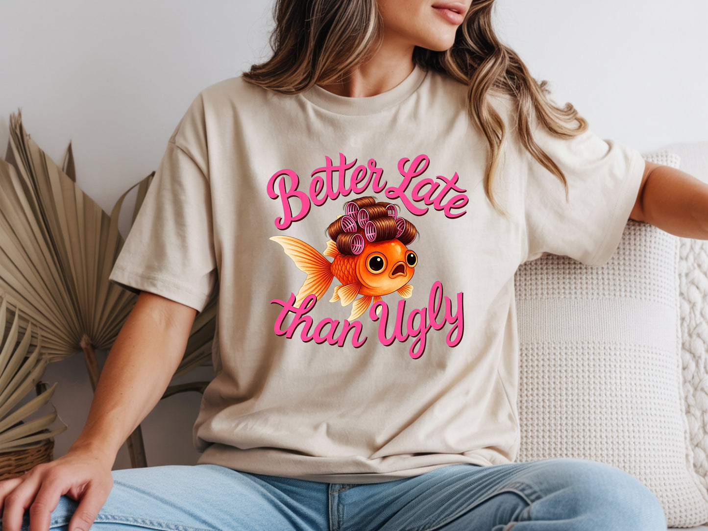 Person wearing beige unisex cute fish t shirt with “Better Late Than Ugly” sarcastic quote and glam goldfish design