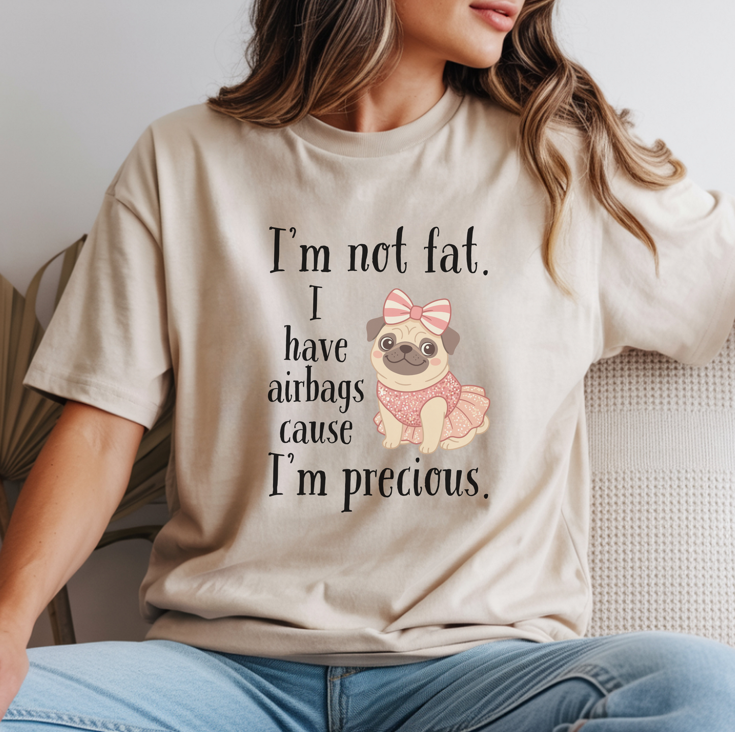 Woman wearing beige funny graphic tee featuring the “I’m Not Fat, I Have Airbags Cause I’m Precious” quote.