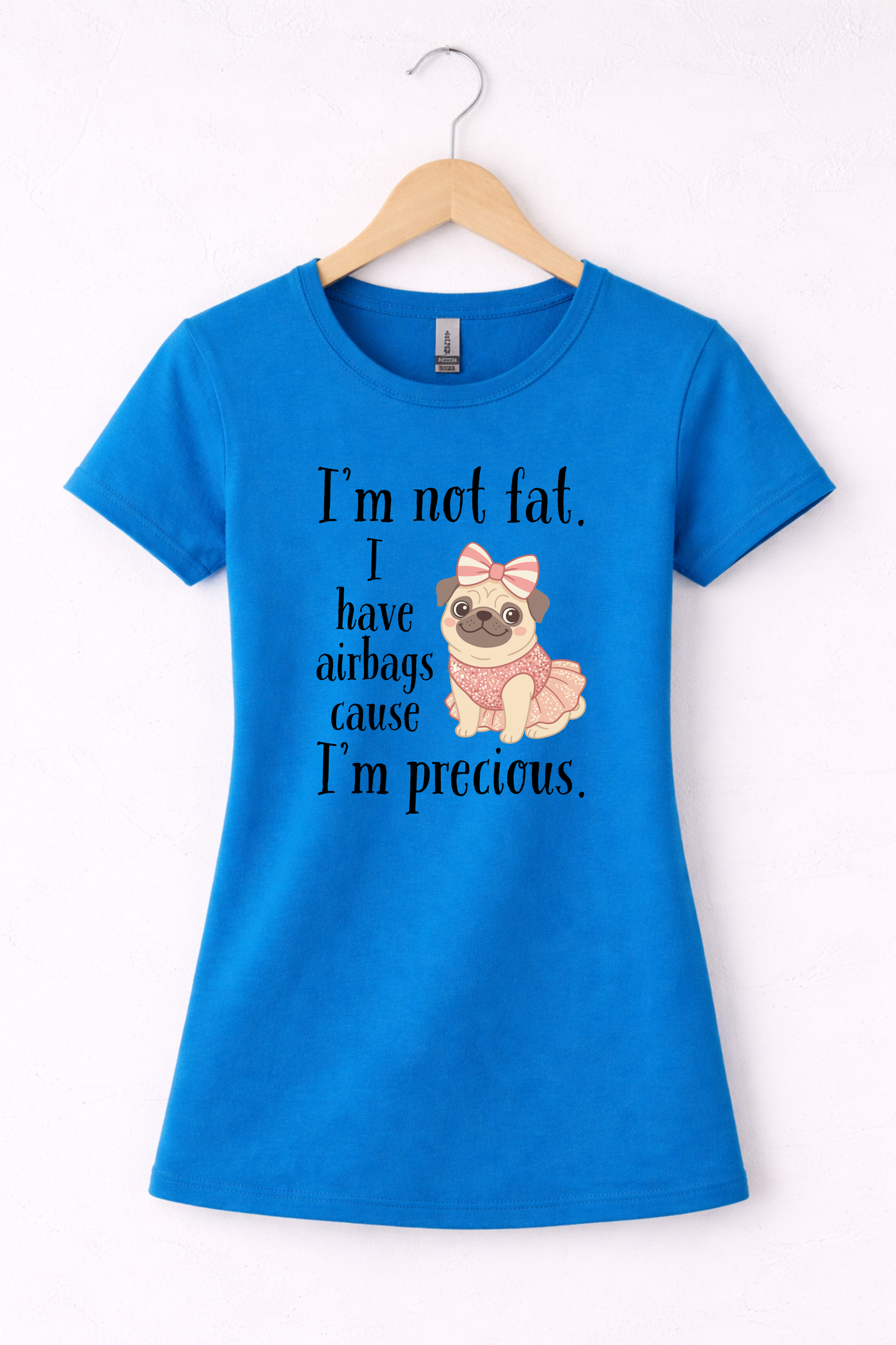 Blue women’s funny graphic crewneck t shirt hanging on wooden hanger featuring the “I’m Not Fat, I Have Airbags Cause I’m Precious” design.