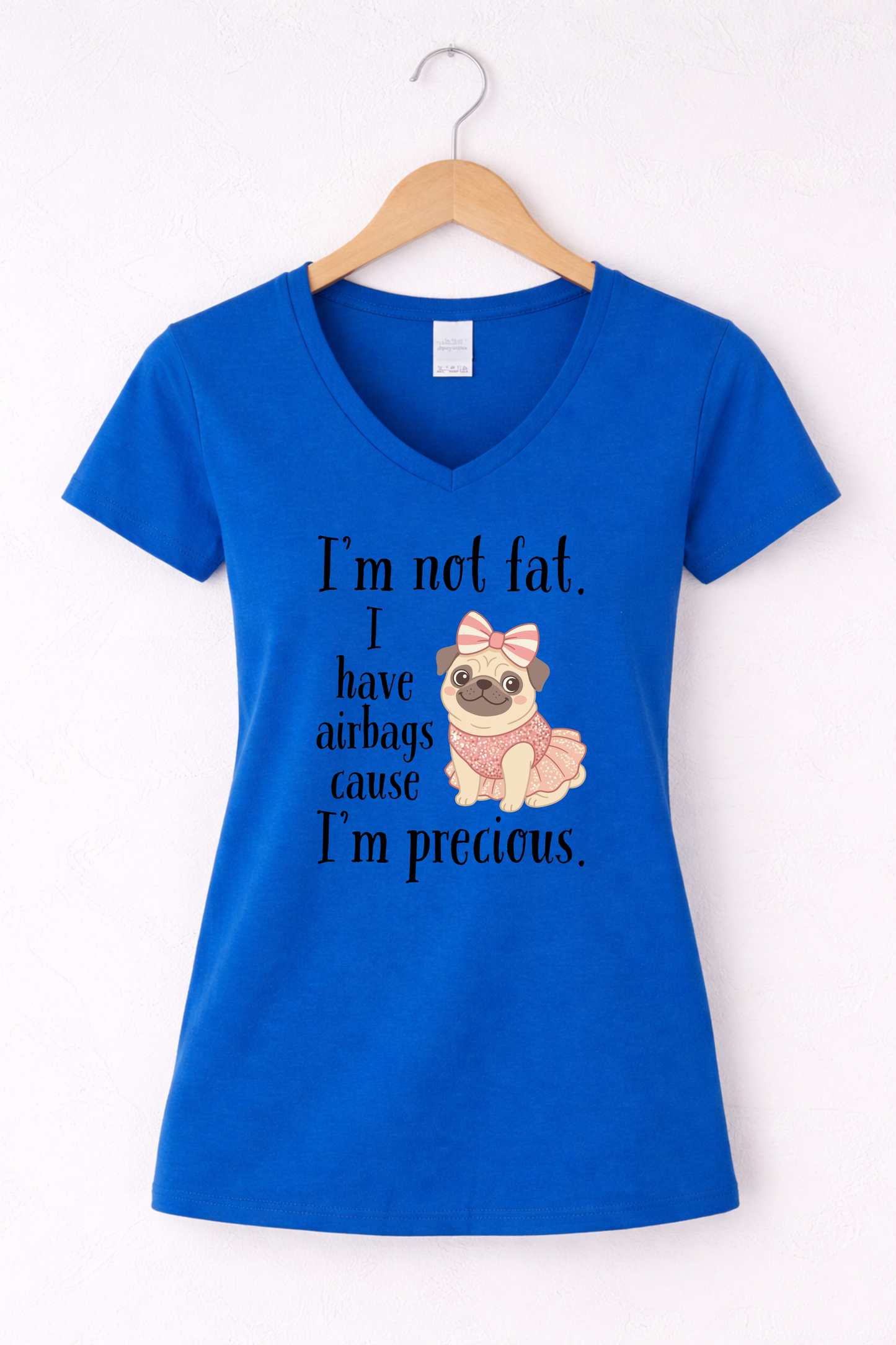 Blue women’s funny graphic V-neck t shirt hanging on wooden hanger with “I’m Not Fat, I Have Airbags Cause I’m Precious” quote.