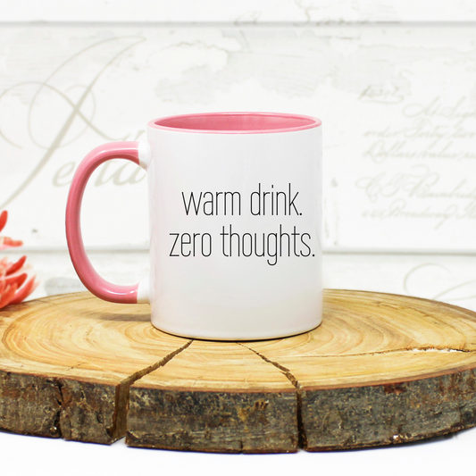 White mug with pink handle and 'warm drink. zero thoughts. text. 