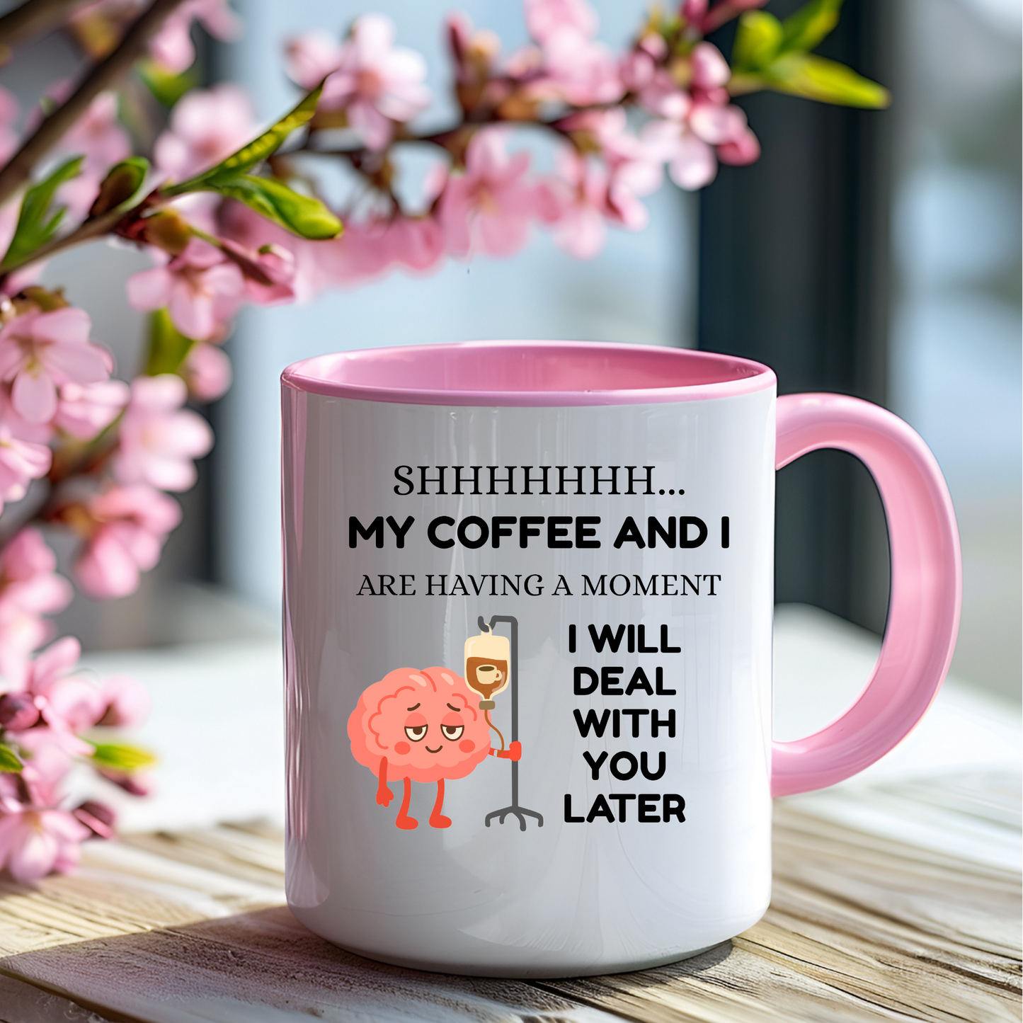 A pink funny coffee lover mug with "shhhh my coffee and I are having a moment, I will deal with you later" text and a cute graphic of a brain holding an IV pole with coffee going in the IV.