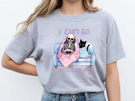 Person wearing grey unisex cat lover graphic tee with “I Can’t Go My Cat Said No” quote and skeleton cat design