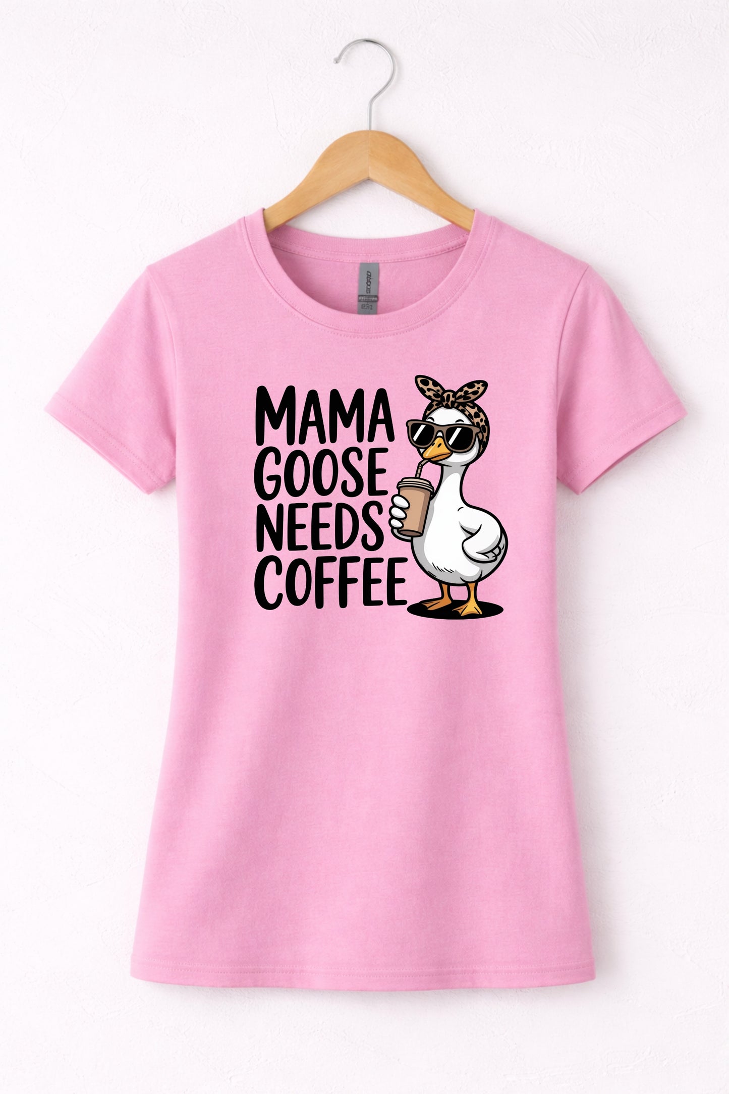 Mama needs coffee shirt with cute "Mama goose needs coffee" text and goose graphic on a pink women's crewneck shirt.