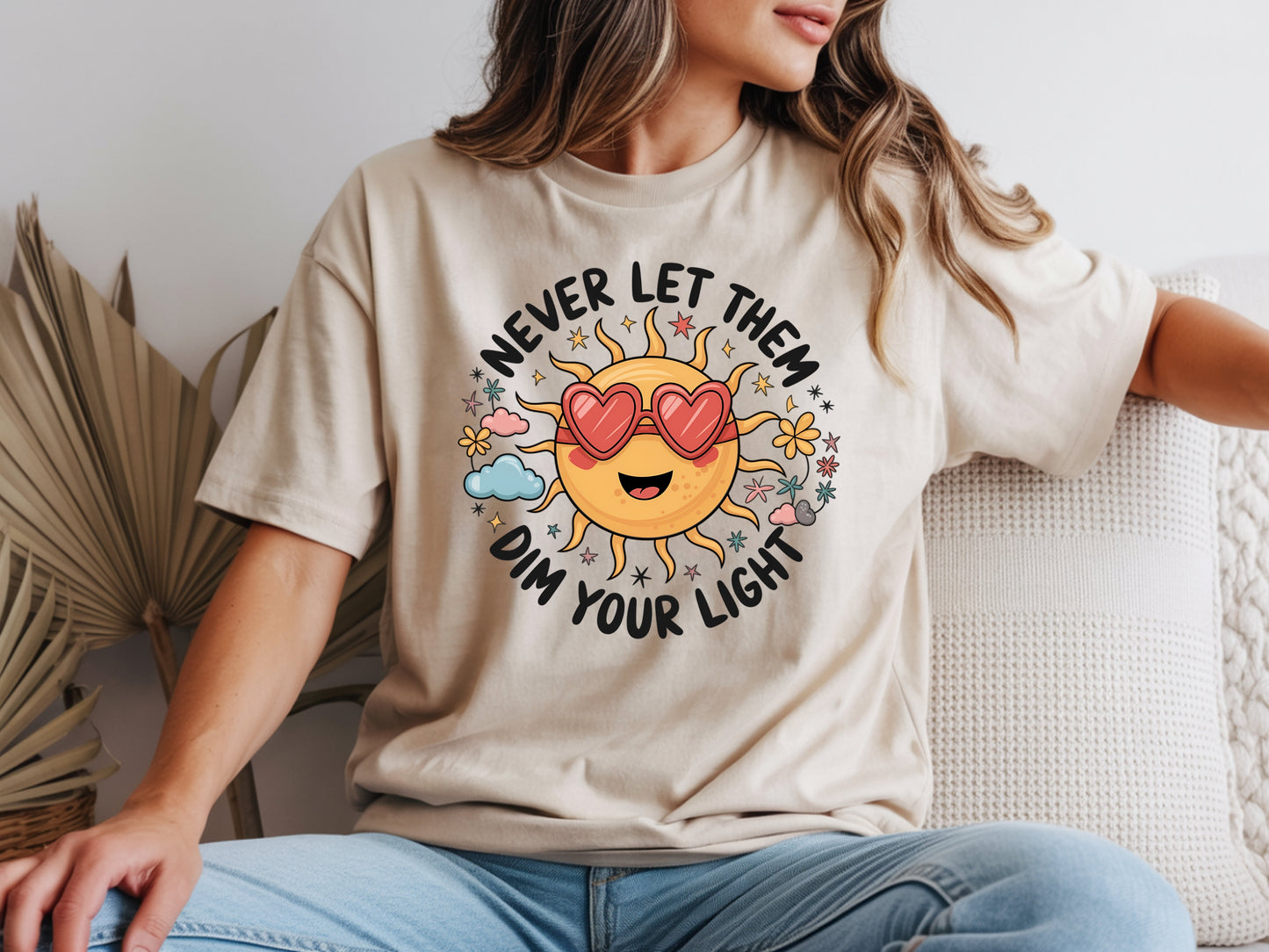 Never let them dim your light shirt with a cute sun graphic and "Never let them dim your light" text on a beige unisex shirt.