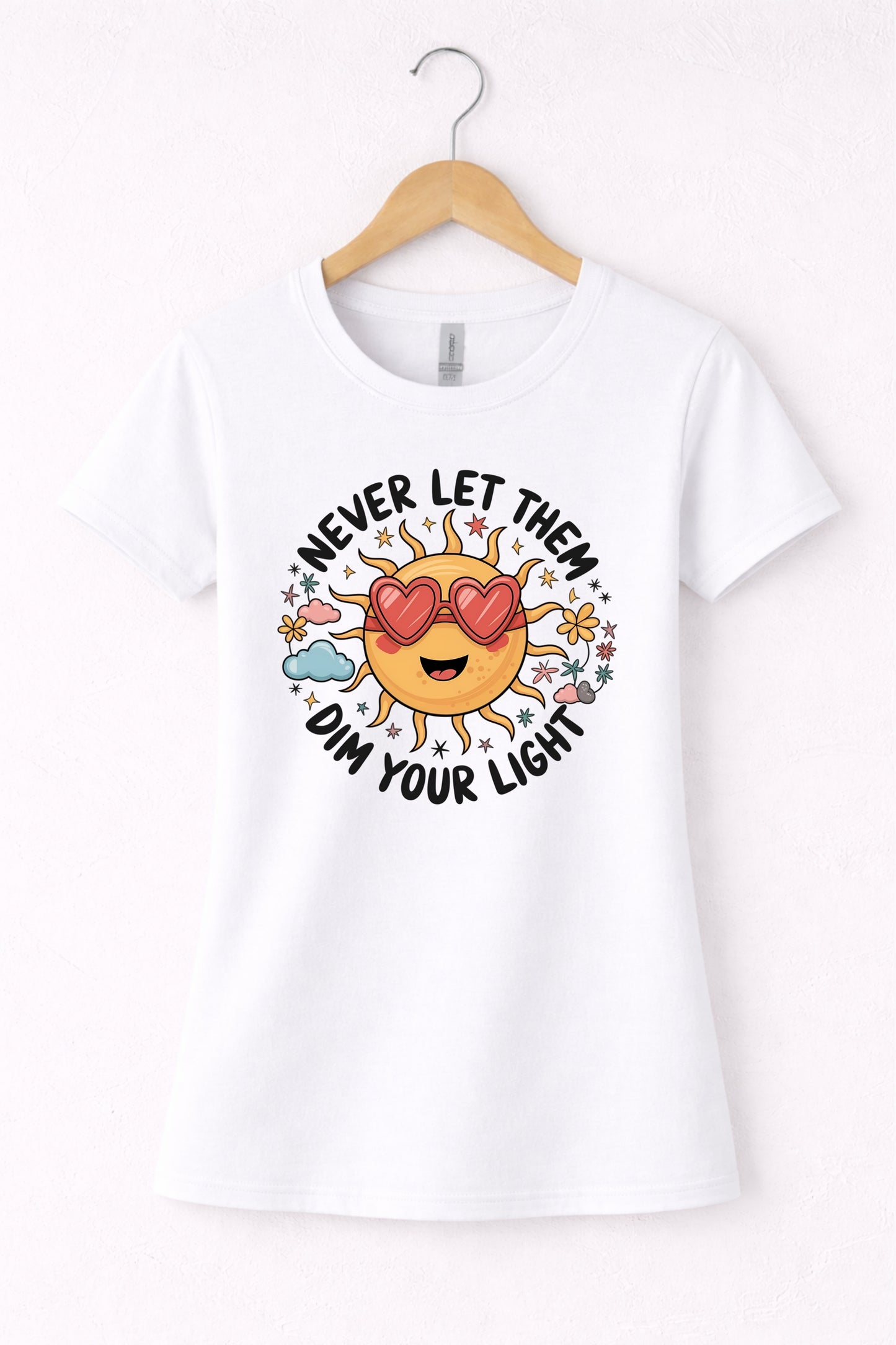 Never let them dim your light shirt with a cute sun graphic and "Never let them dim your light" text on a white women's crewneck shirt.