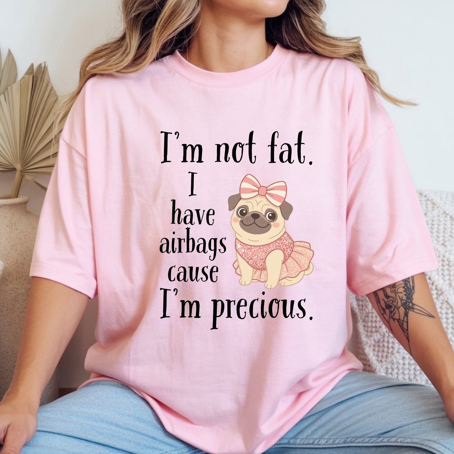 Woman wearing pink funny graphic tee featuring the “I’m Not Fat, I Have Airbags Cause I’m Precious” quote.