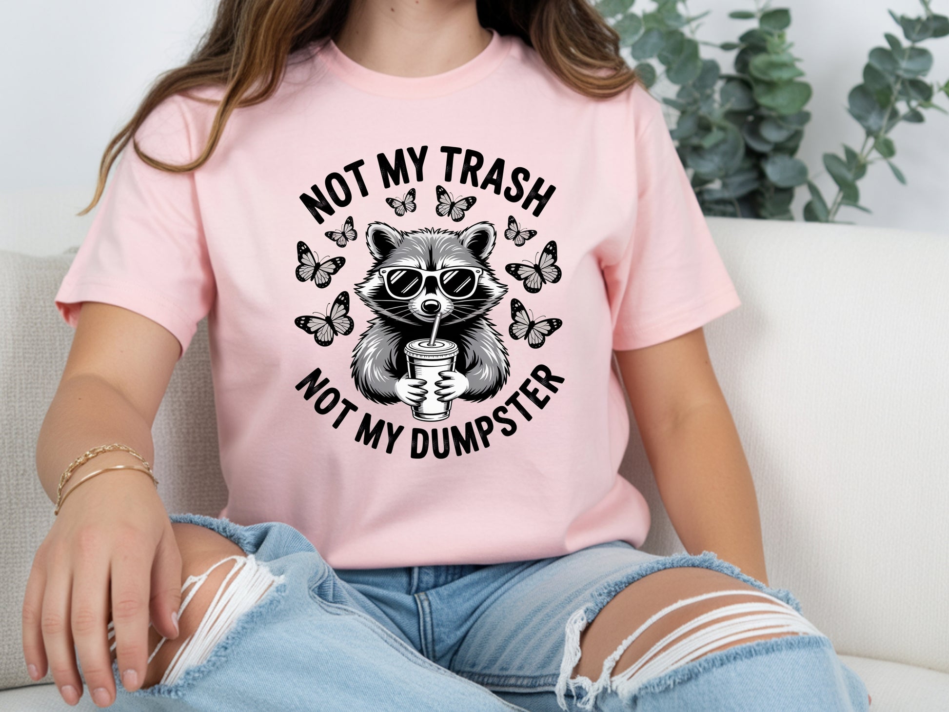 Pink raccoon shirt in oversized unisex fit featuring “Not My Trash Not My Dumpster” quote with a raccoon and butterflies. 