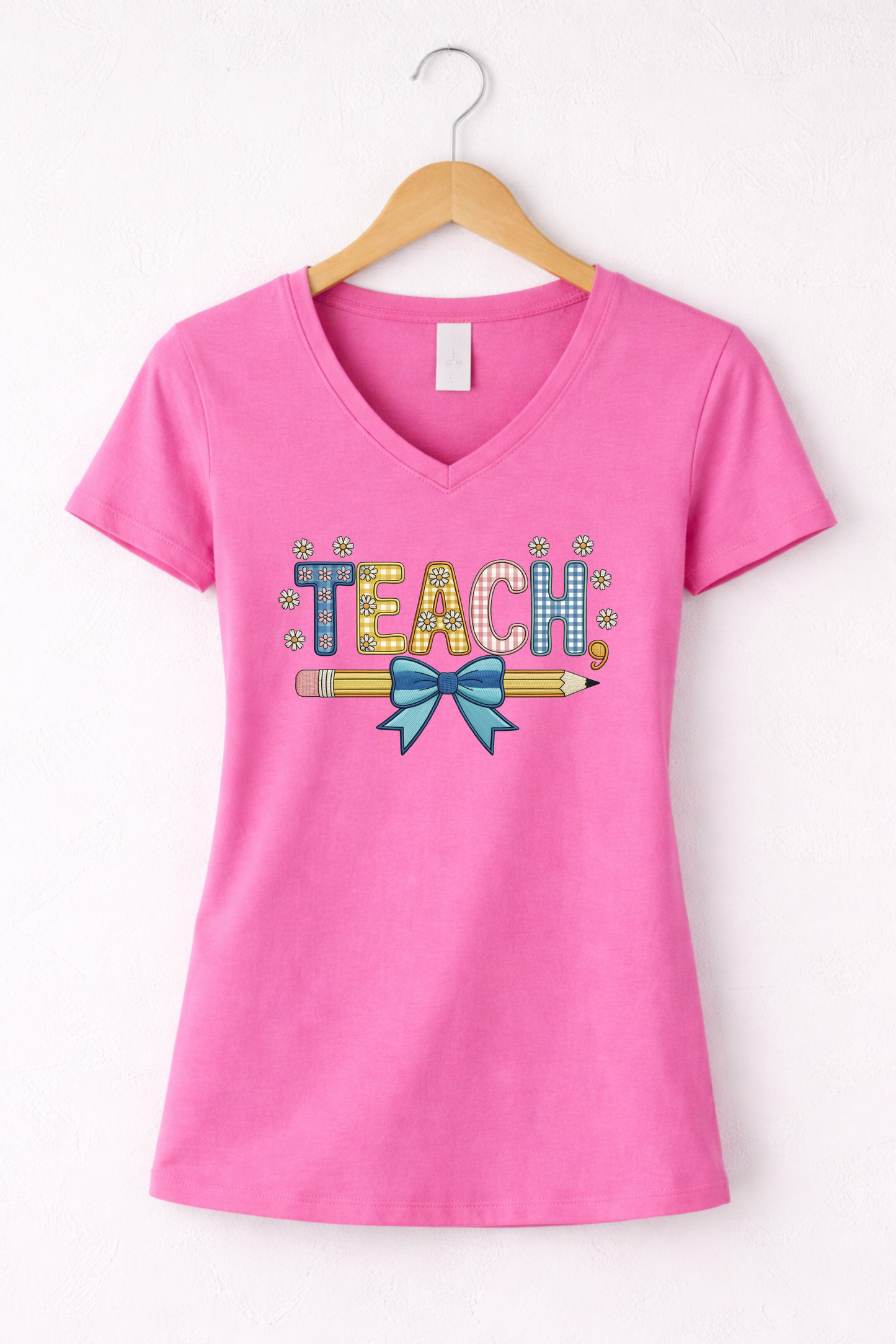 Teacher shirt for women with a cute pencil with blue bow graphic and "Teach" text on a pink women's v-neck tshirt. 