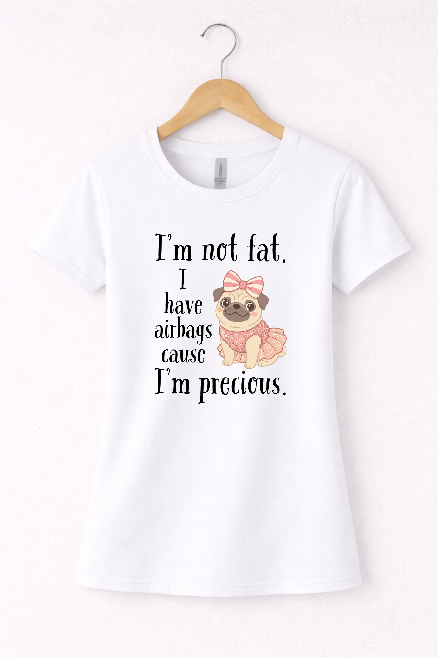 White women’s funny graphic crewneck t shirt hanging on wooden hanger featuring the “I’m Not Fat, I Have Airbags Cause I’m Precious” design.