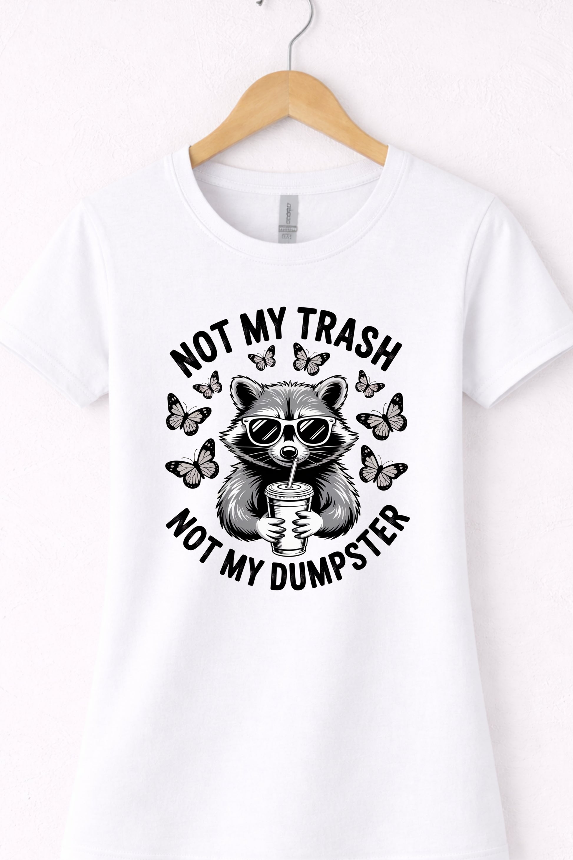 White women’s crewneck raccoon shirt hanging flat with “Not My Trash Not My Dumpster” graphic.